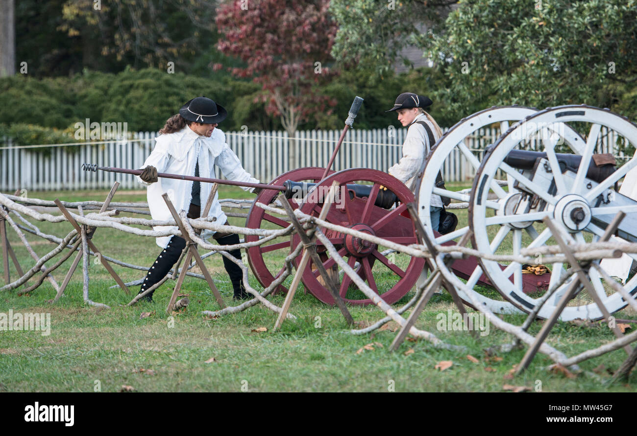 Zwei colonials laden ein rotes Rad Kanone zum Brennen am Ende des Tages an der historischen Colonial Williamsburg. Stockfoto