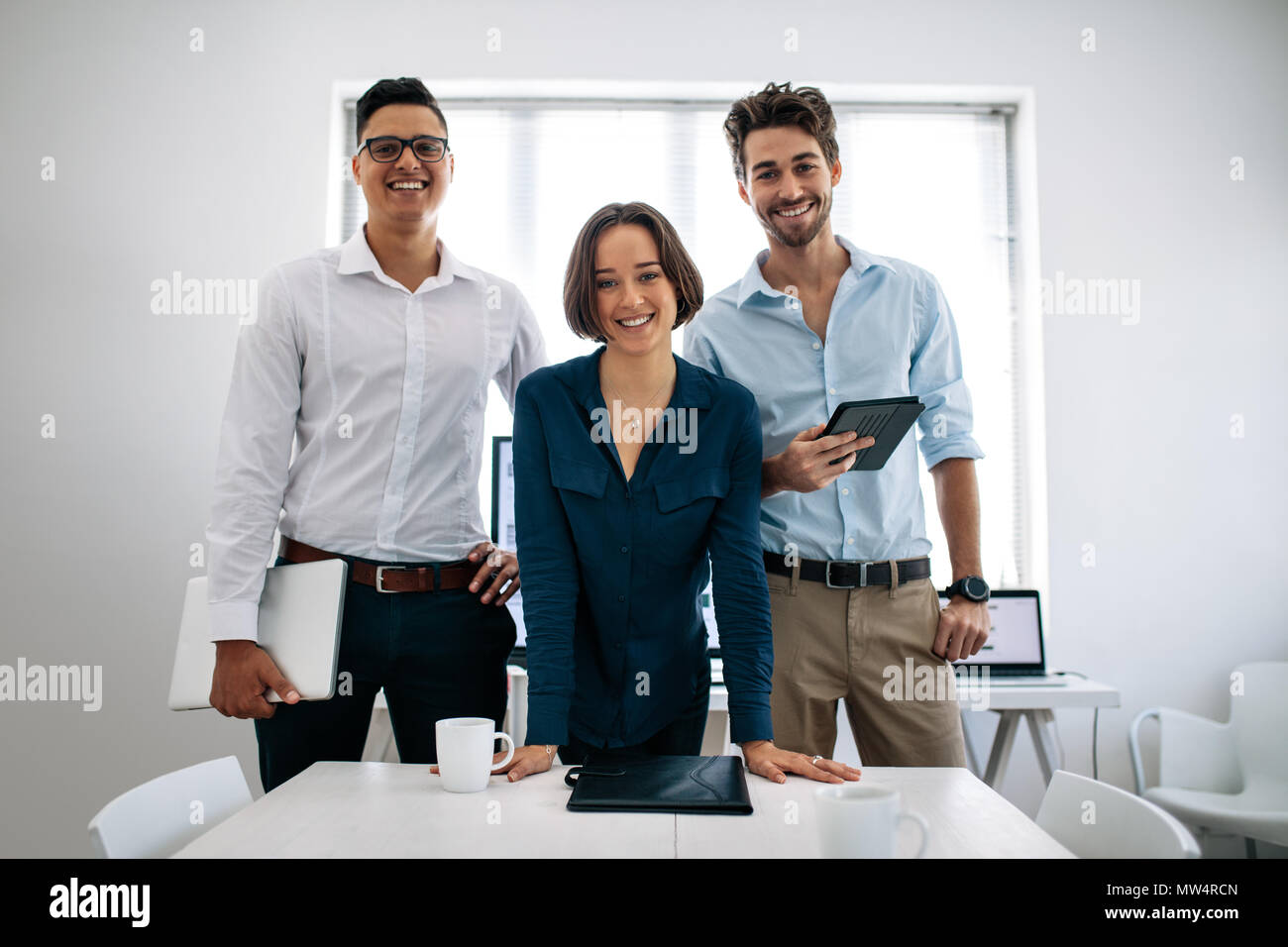 Geschäftsleute in Konferenzraum holding Notebook und Tablet-PC stehen. Team von lächelnden Anwendungsentwickler in der Sitzung Raum stehen im Büro Stockfoto