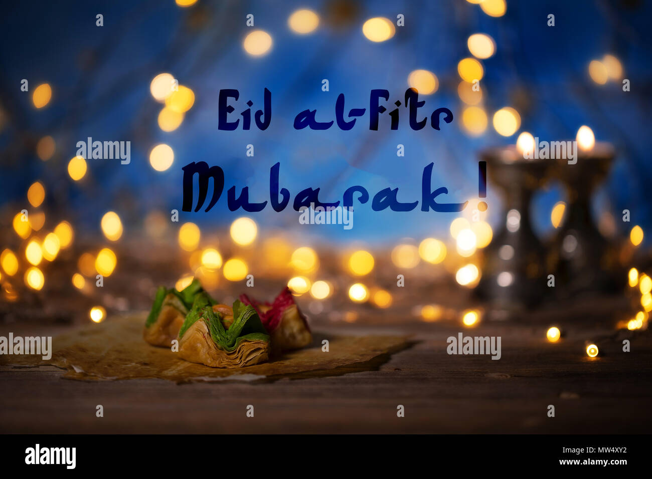 Gratulation: Eid Mubarak! Arabische Süßigkeiten auf einer hölzernen  Oberfläche. Kerzenständer, Nacht Licht und Nacht blauer Himmel mit Halbmond  im Hintergrund Stockfotografie - Alamy