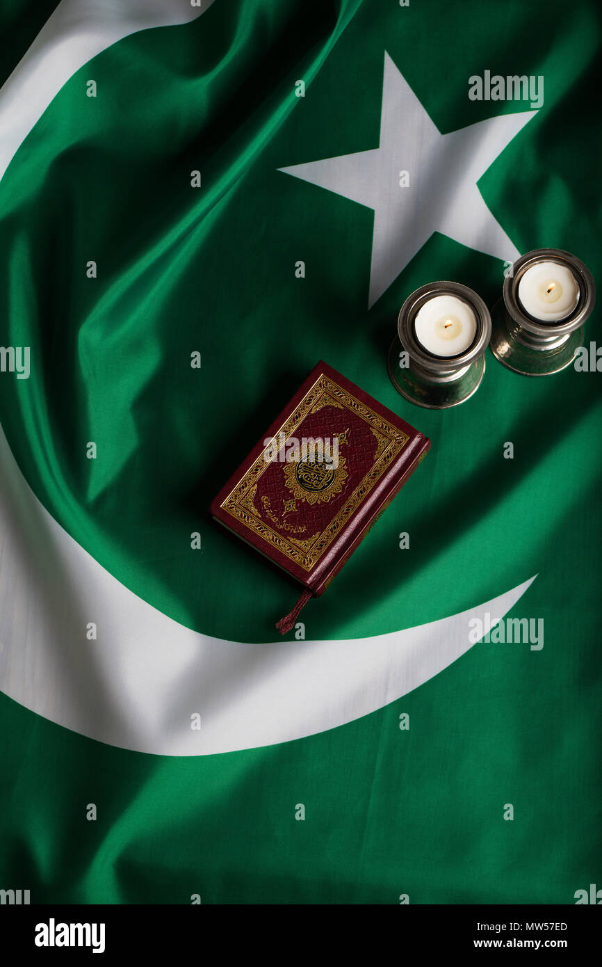 Koran und Kerzen auf der Flagge von Pakistan. Übersetzung in Englisch - das  Buch enthält Verse des Koran Stockfotografie - Alamy