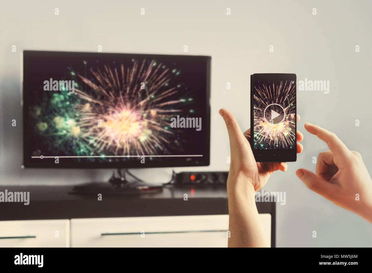 Mann mit Smartphone an einen TV Video zu Hause angeschlossen. Übertragen Sie Videos vom Telefon auf den TV-Bildschirm. Moderne Geräte. Die Informationsübertragung zwischen Dev Stockfoto
