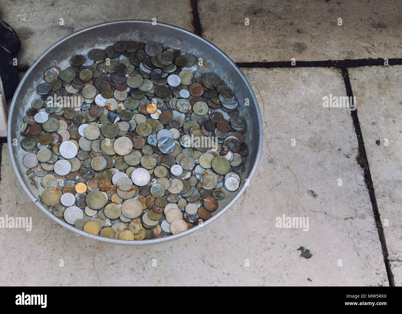 Eine Streuung von alten Münzen in Dose Ware auf dem Steinboden. Stockfoto