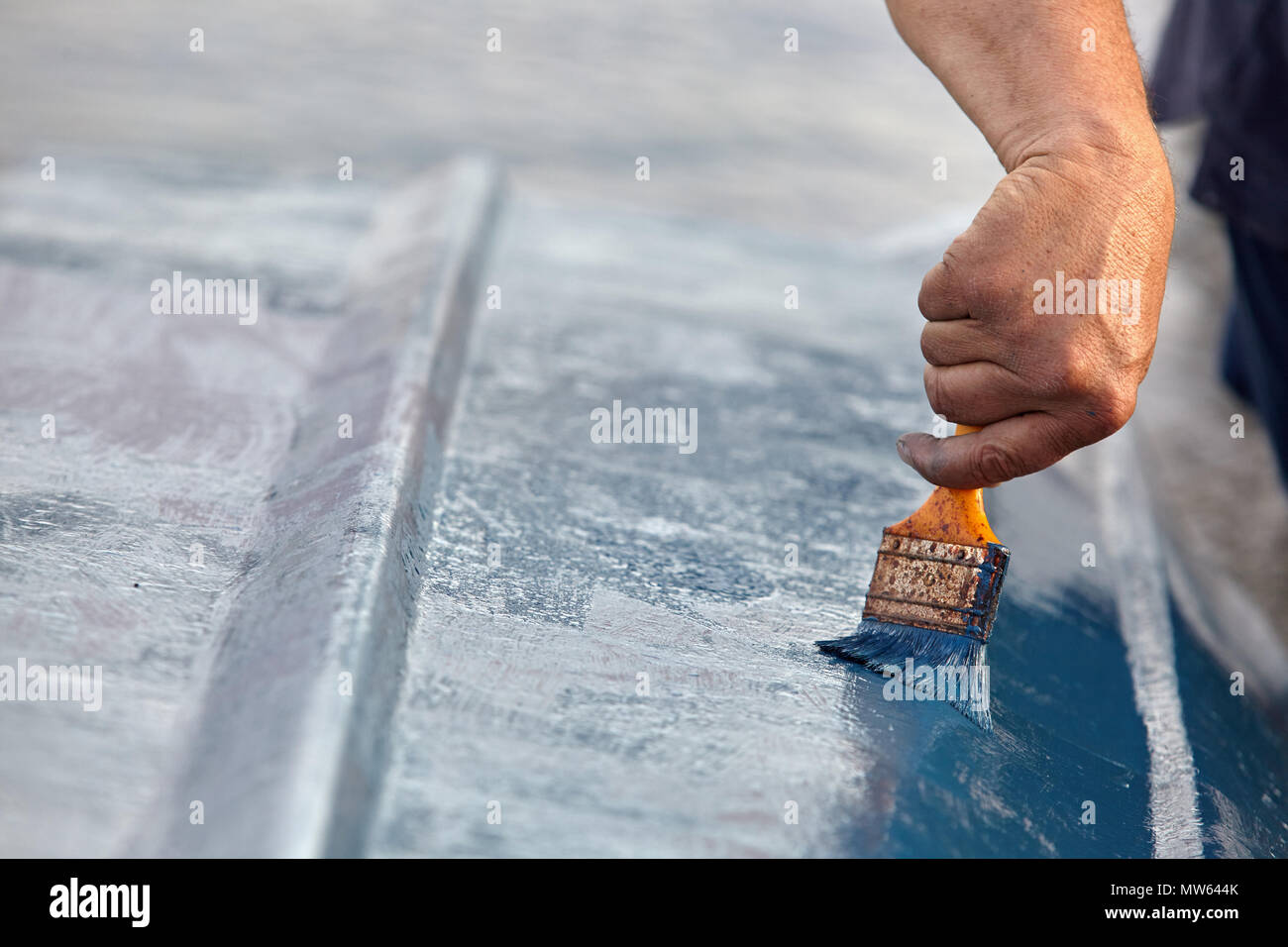 Mann Malerei Boot. Detailansicht von Hand mit einem Pinsel mit blauer Farbe. Stockfoto