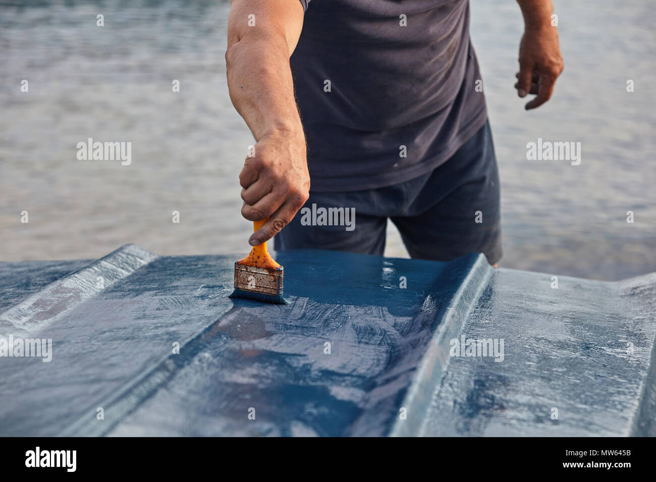 Mann Malerei Boot. Detailansicht von Hand mit einem Pinsel mit blauer Farbe. Stockfoto