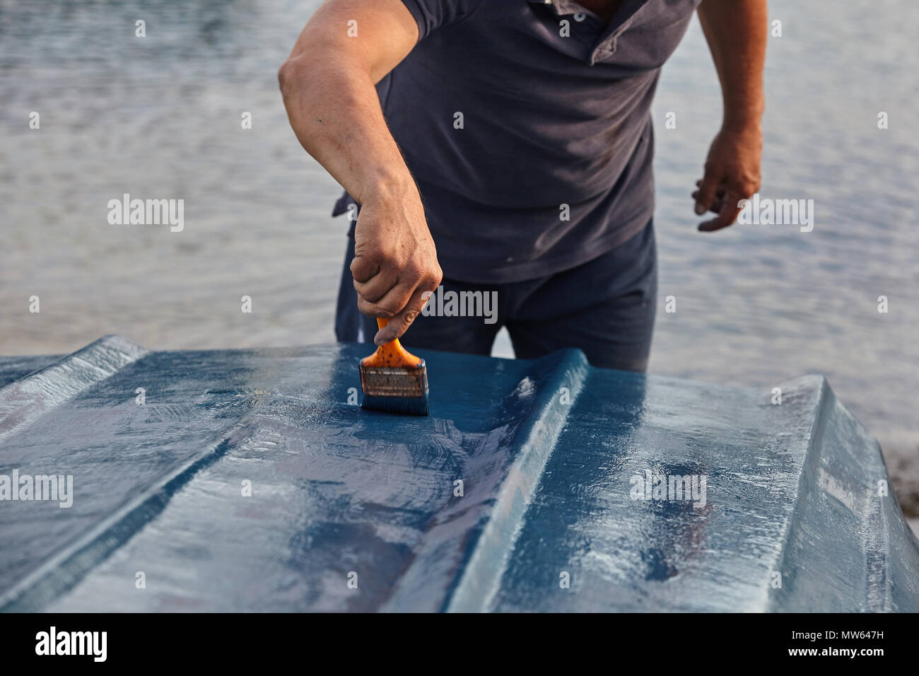 Mann Malerei Boot. Detailansicht von Hand mit einem Pinsel mit blauer Farbe. Stockfoto