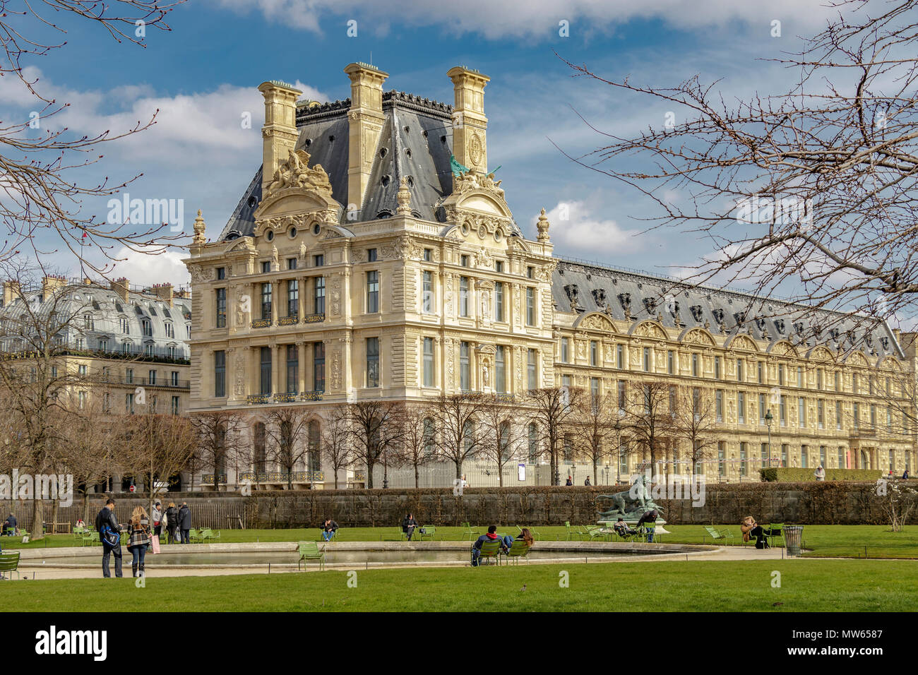 Menschen, Entspannung in der Wintersonne im Jardin des Tuileries mit Pavillon de Marsan Teil des Louvre Museum im Hintergrund, Paris Stockfoto