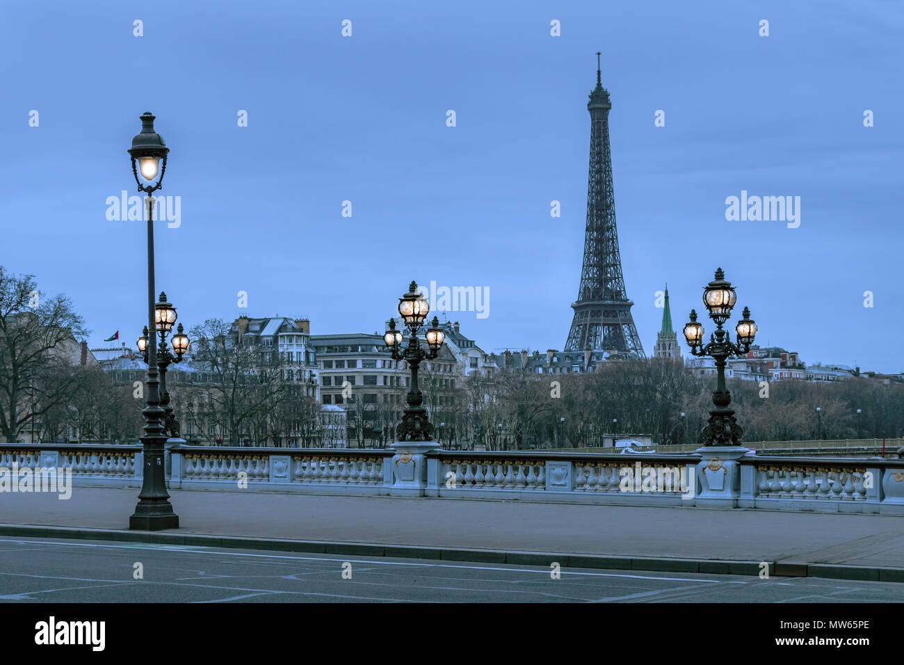 Beleuchtete Lampen in der Dämmerung auf der Brücke Pont Alexandre III mit dem Eiffelturm in der Ferne, Paris, Frankreich Stockfoto