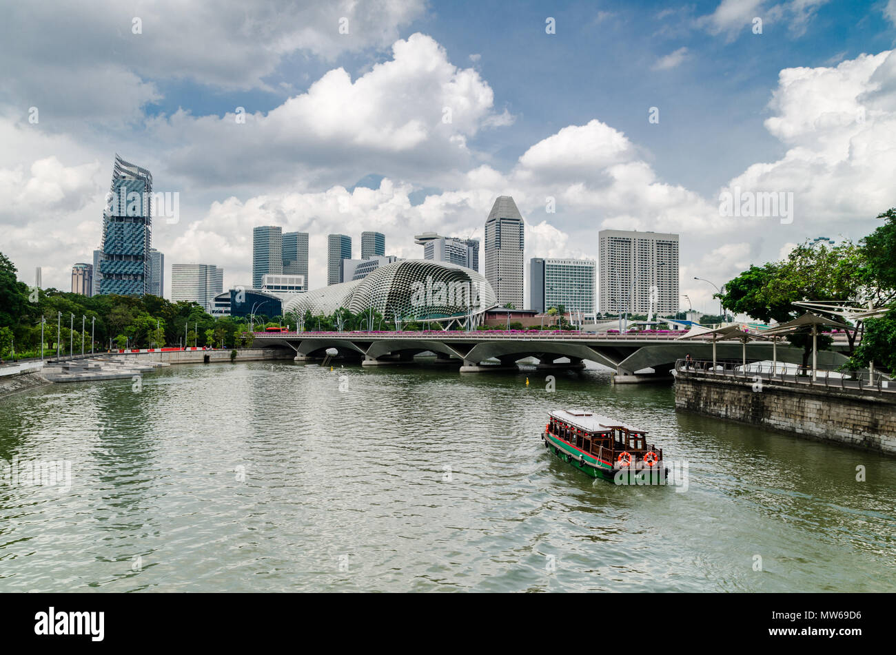 Eine Kreuzfahrt Boot wie die twakows Fahrt durch die berühmten Singapore River bekannt. Das Gebäude an der Rückseite ist die berüchtigte Theater an der Bucht, Esplanade. Stockfoto