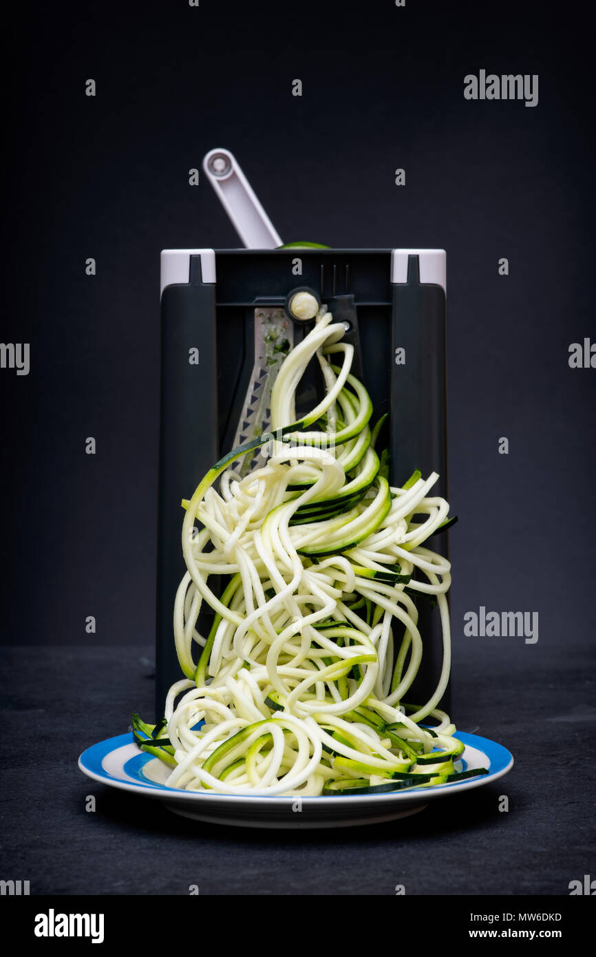 Spiralizing Zucchini vor einem dunklen Hintergrund Stockfoto