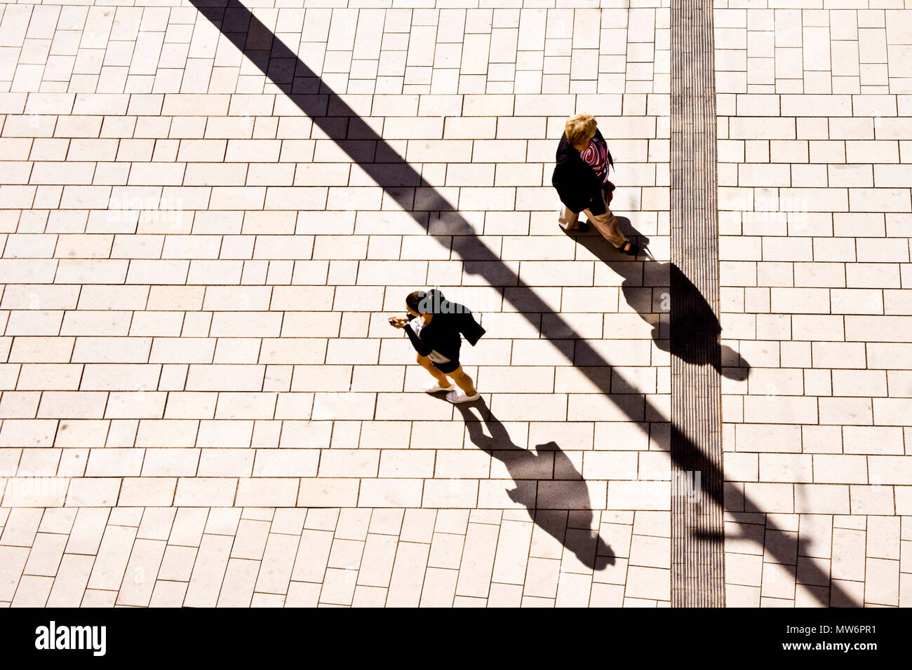 Zwei Frauen zu Fuß auf der Straße an einem sonnigen Tag, Schatten auf dem Gehsteig projiziert, Ansicht von oben Stockfoto