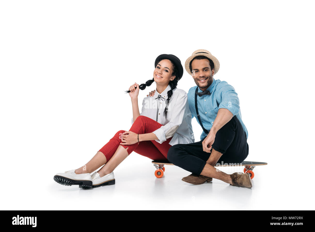 Junge stilvollen afrikanischen amerikanischen Paar sitzt auf Skateboard und Kamera Stockfoto