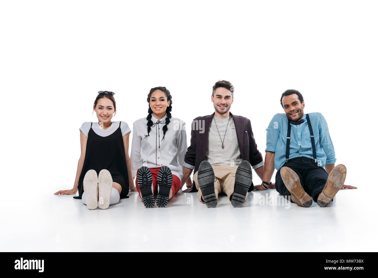 Lächelnd multiethnischen Freunde sitzen auf dem Boden und Kamera Stockfoto