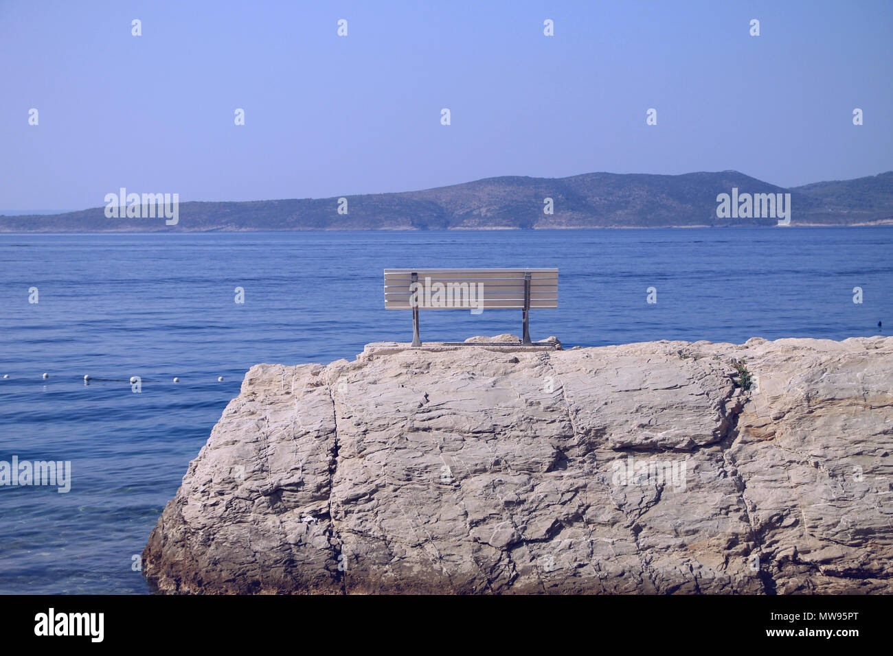 Weiße Sitzbank auf Felsen in der Nähe der Adria in Brela, Kroatien Stockfoto