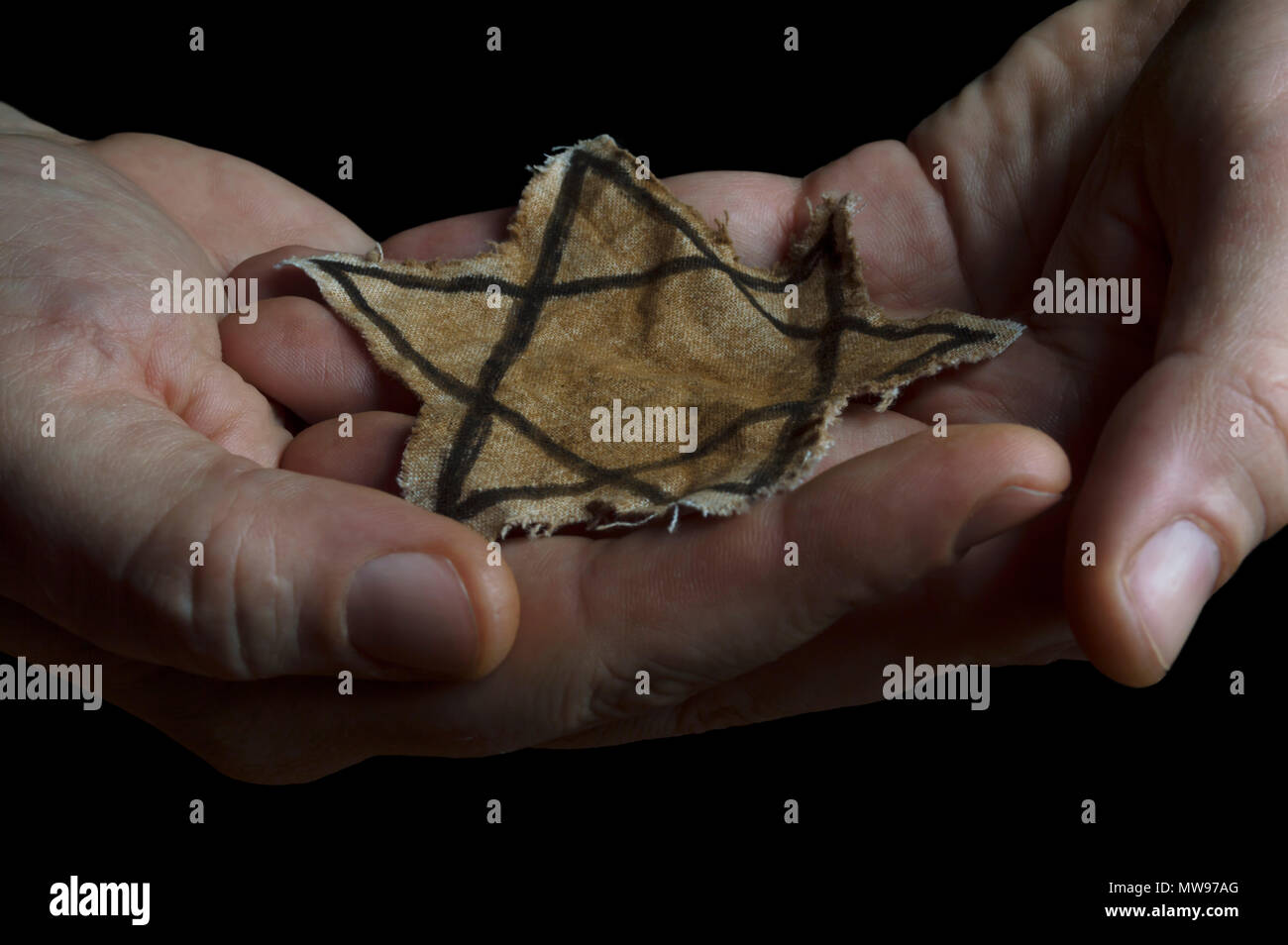 Nahaufnahme einer zerfetzten Jüdischen Abzeichen in den Händen eines Mannes Stockfoto