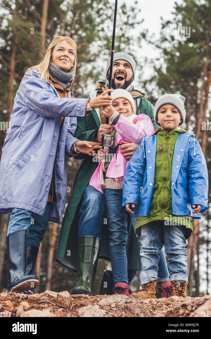 Glückliche junge Familie in regenmäntel zusammen Angeln Stockfoto