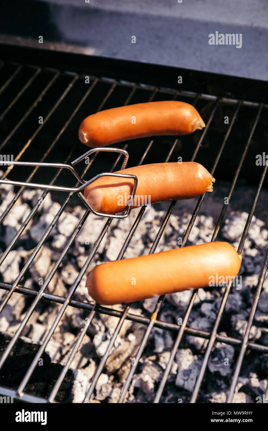 Mit Zange einstellen Würstchen vom Grill im Außenbereich Grill Stockfoto