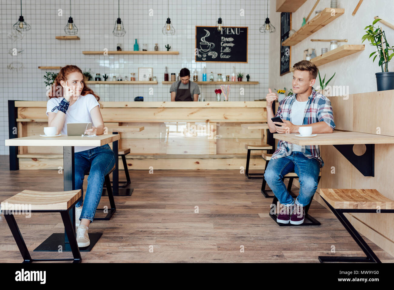 Glückliche junge Mann und Frau mit digitalen Geräten Lächeln, während Sie sich im Cafe zu wissen Stockfoto