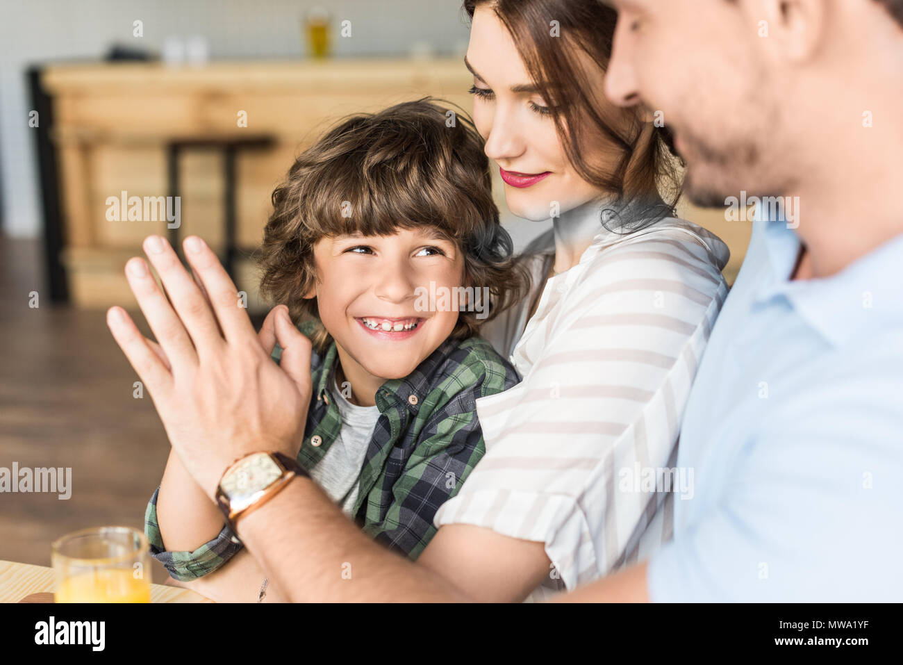 Vater hoch fünf zu seinem Sohn, der auf Mütter Knie Stockfoto