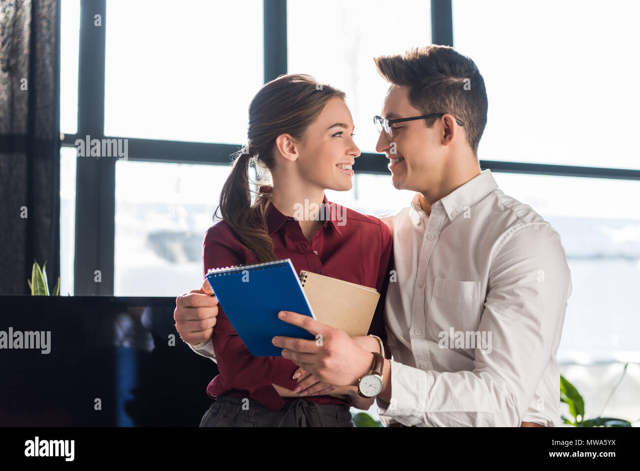 Attraktive junge Führungskräfte Paar umarmen im Büro, Arbeitsplatz Romantik Konzept Stockfoto