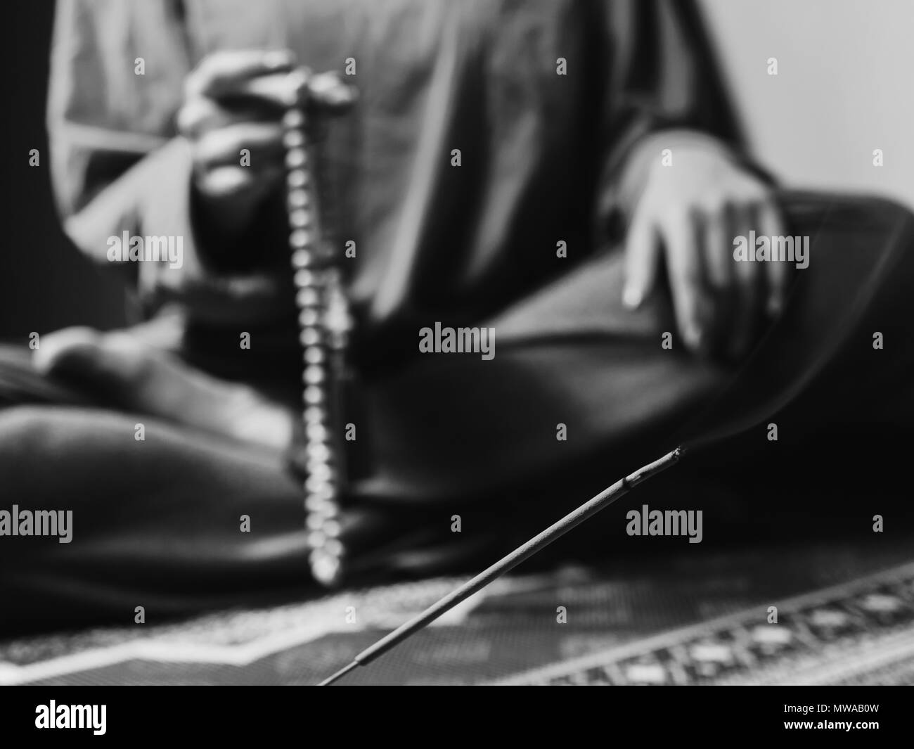 Konzentriert betende Frau mit Holz Rosenkranz mala Perlen. Nahaufnahme, auf Räucherstäbchen konzentrieren. Schwarz und Weiß Stockfoto