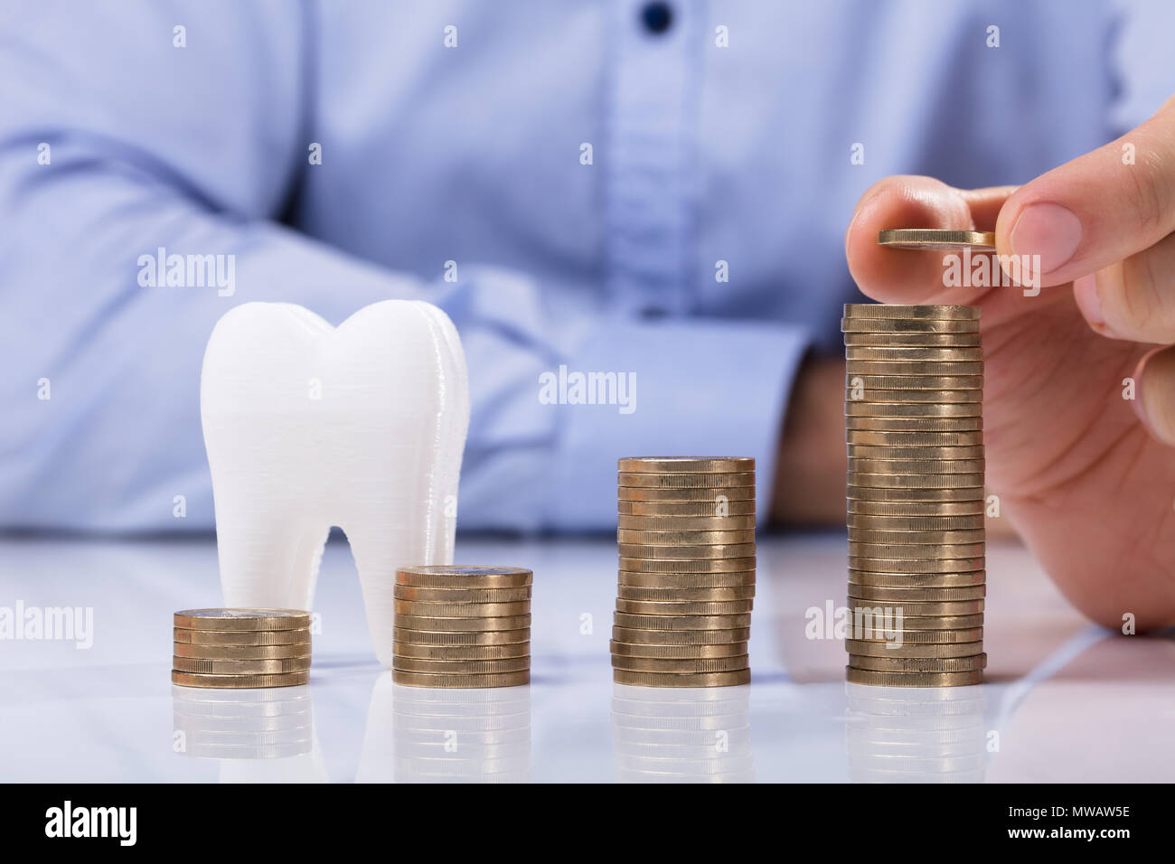 Mann die Münze auf dem Stapel Münzen Vor der Weißen Zahn Stockfoto