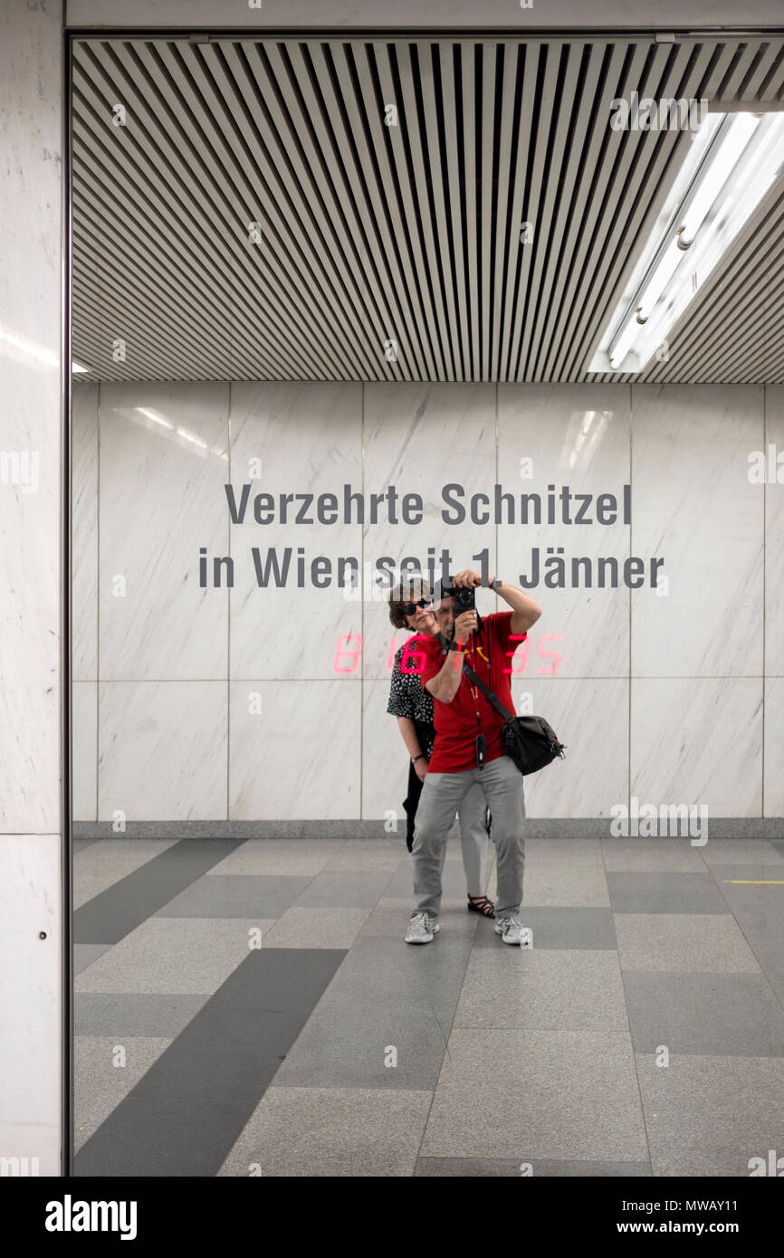 Ein Fotograf & Frau nehmen eine selfie in einer Wiener U-Bahn station mit einer Installation, die in Echtzeit zählt, die Anzahl der Schnitzel gegessen. Stockfoto