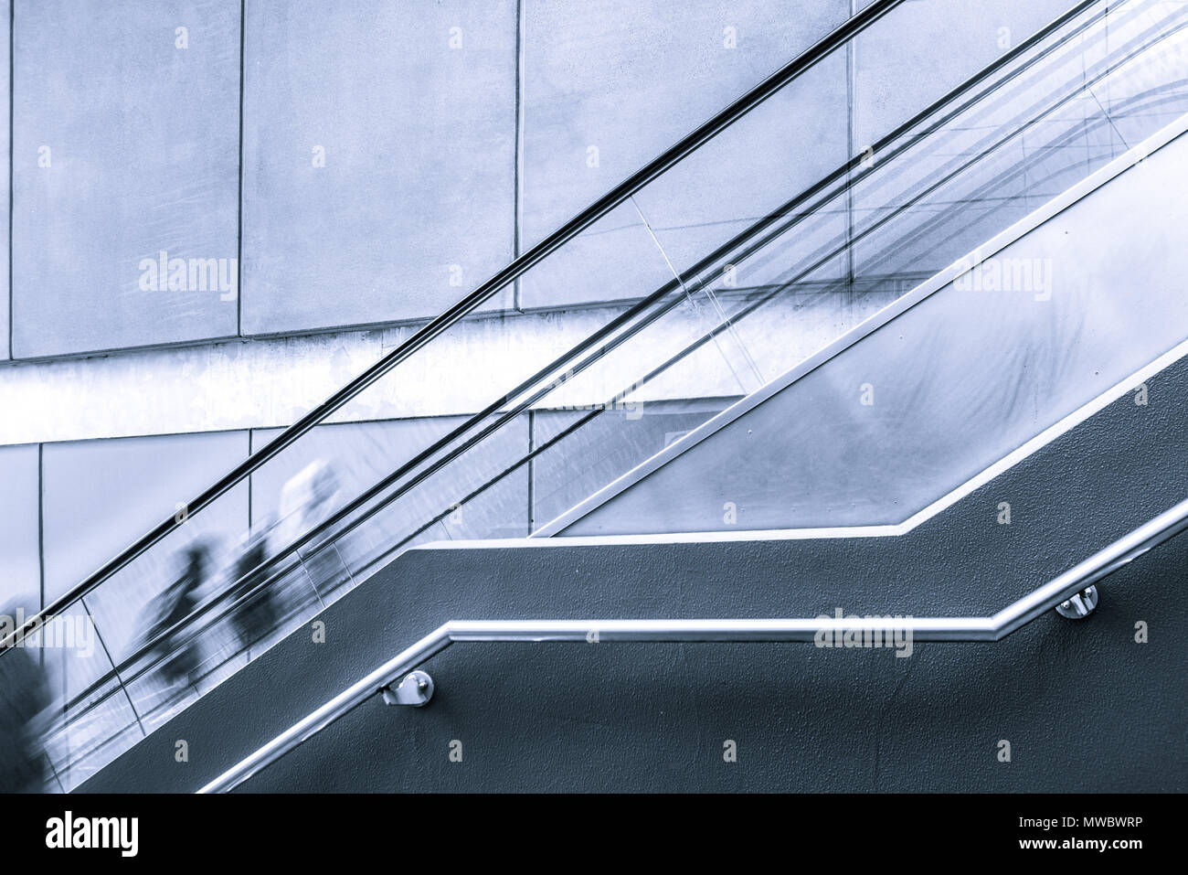 Verschwommene Bewegung der Menschen auf der Rolltreppe mit Kopieren in Schwarz und Weiß Stockfoto