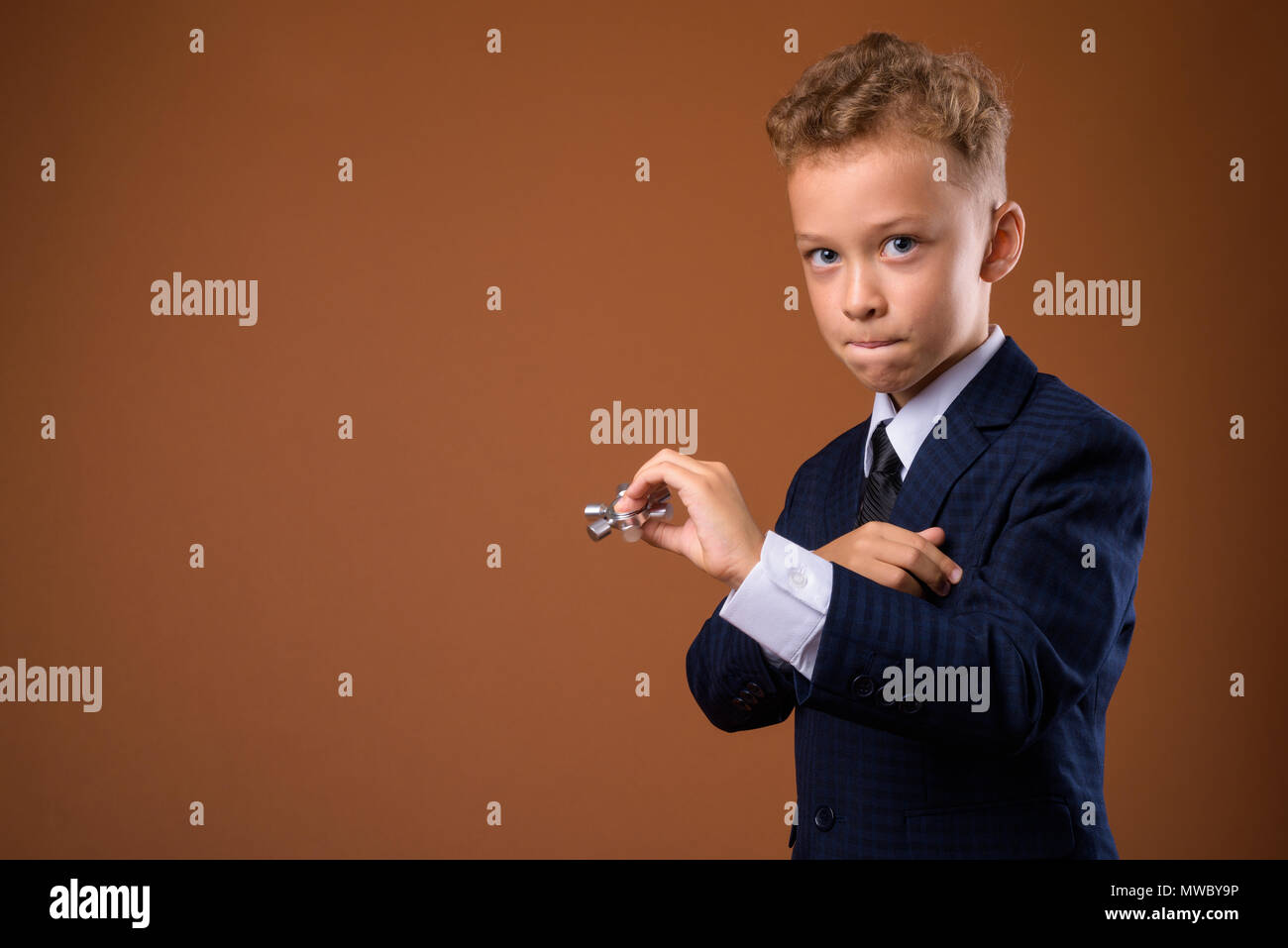 Junge als Geschäftsmann gegen braunen Hintergrund Stockfoto