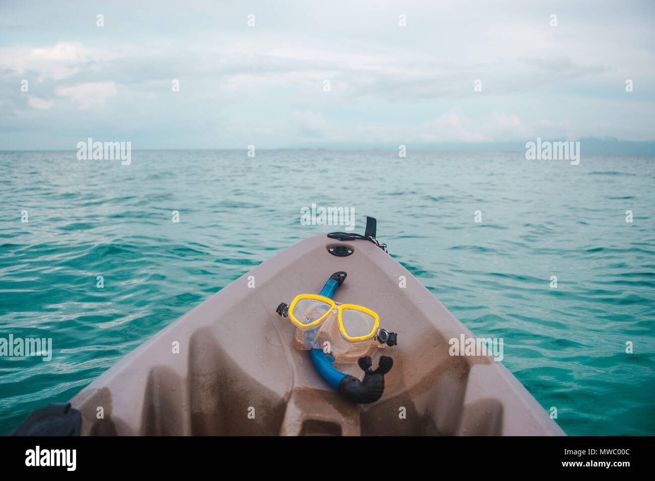Schnorchel blau und gelb Schutzbrille auf der Vorderseite eines braunen Kunststoff Kajak in das türkisfarbene Wasser der Karibik aus den San Blas Inseln, Panama Stockfoto