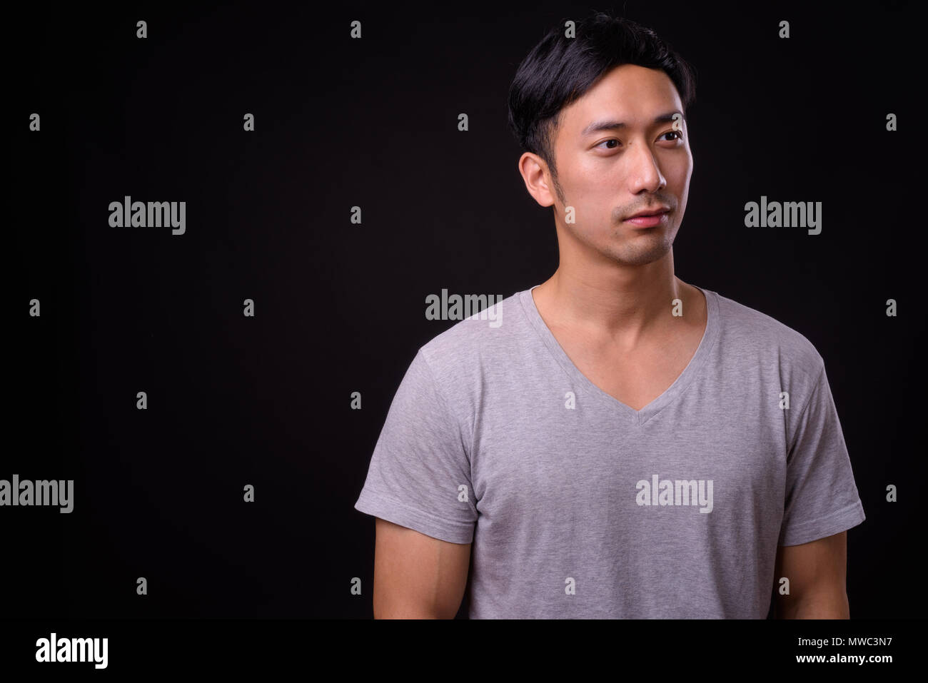 Die Jungen gut aussehenden asiatischer Mann auf schwarzem Hintergrund Stockfoto