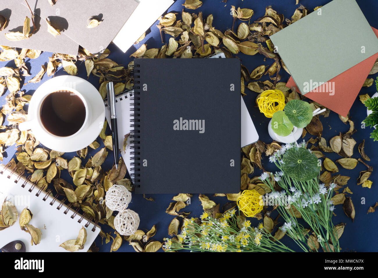 Notepad und Kaffee auf rustikalen blauer Hintergrund mit trockenen Blüten. Stockfoto