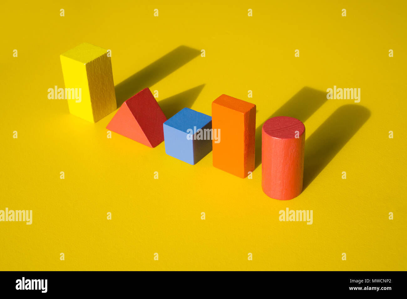 Holz- Bausteine Spielzeug mit Schatten auf gelben Hintergrund. Stockfoto