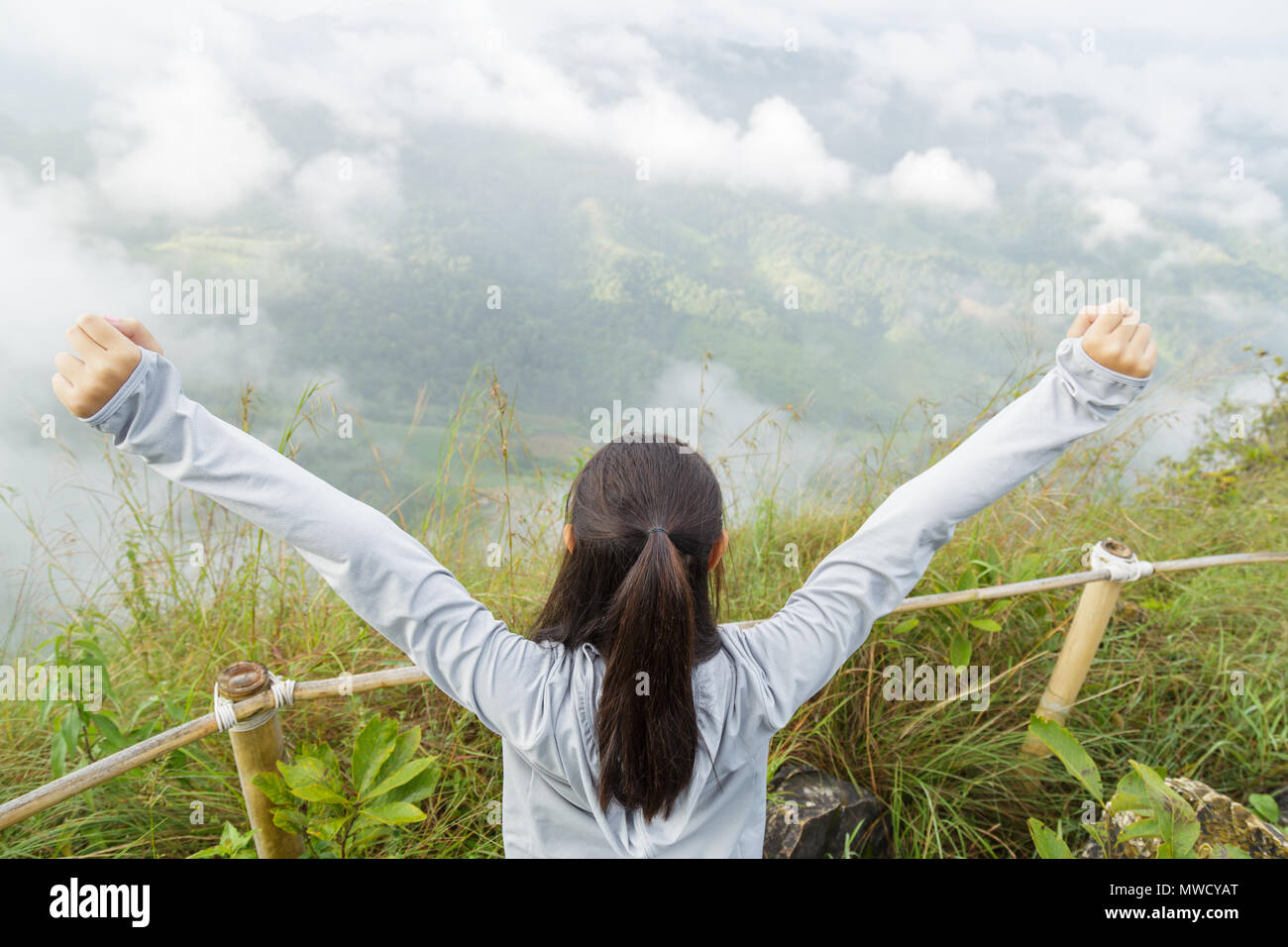 Asien Mädchen entspannen und auf die Berge im Hintergrund aktualisieren" ist eine Landschaft mit hohen Bergen, weiße Wolken und Nebel. Stockfoto