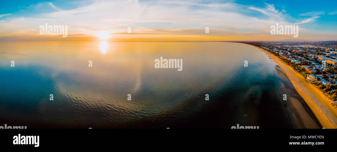 Atemberaubende Luftaufnahmen Panorama der Sonne über glatte Wasseroberfläche mit Cloud Reflexionen Stockfoto