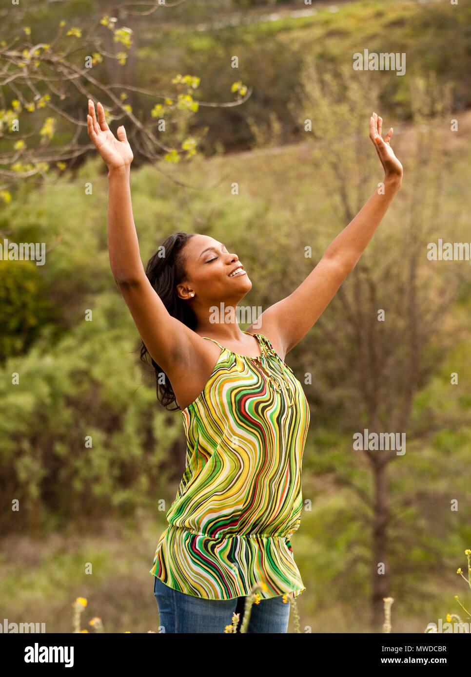 Gerne Frau sitzt in einem Feld lächelnd. Stockfoto