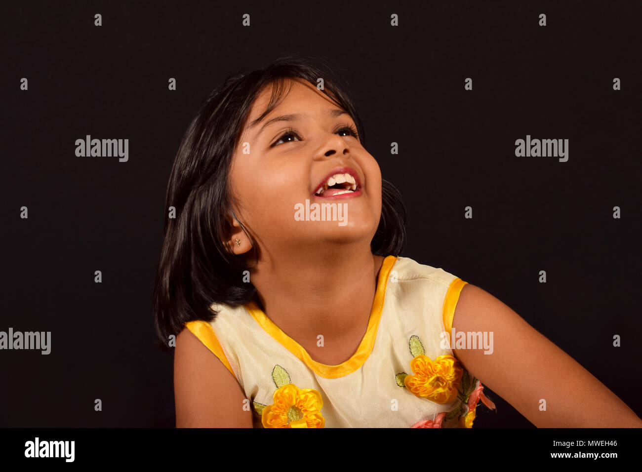 Kleines Mädchen mit einem netten Lächeln von der Kamera auf der Suche vor schwarzem Hintergrund, Pune Stockfoto