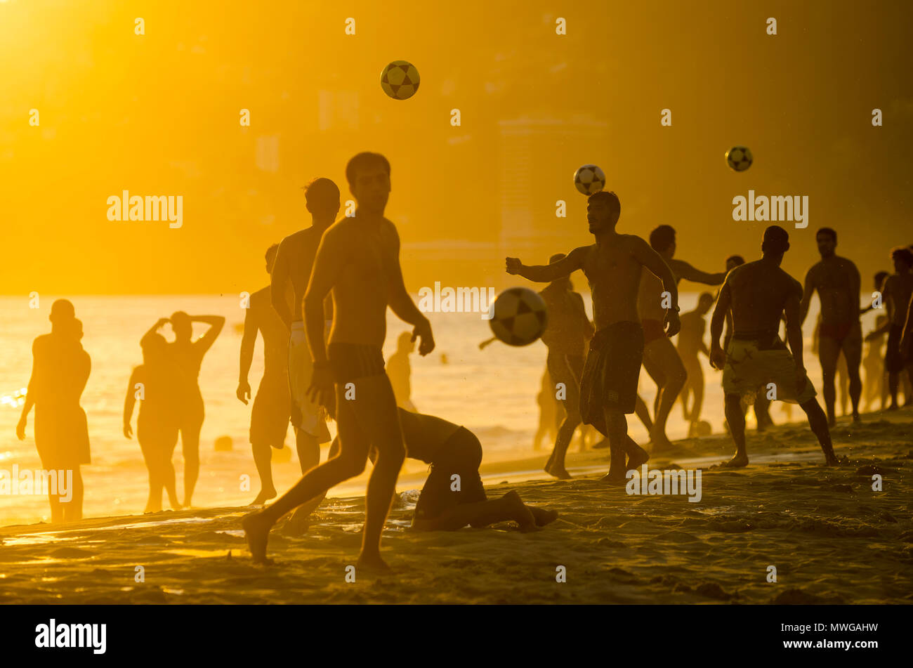 Sonnenuntergang in der Ferne Silhouetten spielen keepy - Uppie Strand Fußball an der Küste in Ipanema Beach Rio de Janeiro. Stockfoto