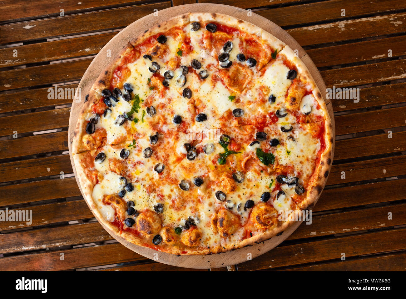 Große margherita Pizza mit schwarzen Oliven auf dunklem Holz Tisch von ... Große margherita Pizza mit schwarzen Oliven auf dunklem Holz Tisch von ...