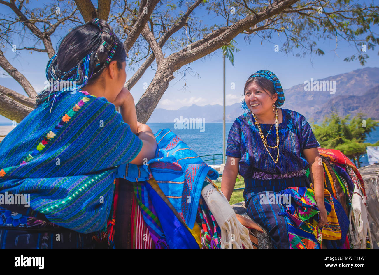 Panajachel, Guatemala - April, 25, 2018: Im freien Blick auf unidentifed indigene Frau, tragen typische Kleidung sprechen Jede otherin vor Atitlan See und Vulkan im Hintergrund in Guatemala Stockfoto