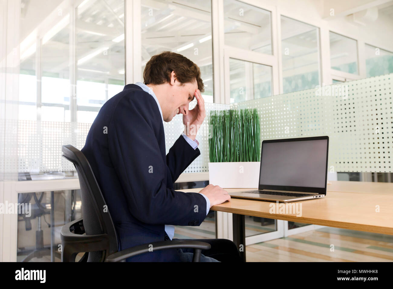 Nachdenklicher Mann mit Laptop im Büro Stockfoto