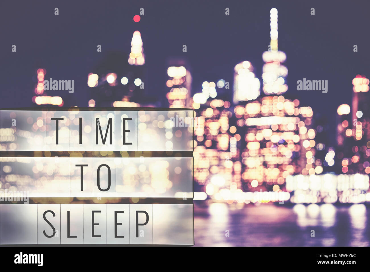 Zeit Text in einem Leuchtkasten zu schlafen, verschwommenes Manhattan bei Nacht im Hintergrund, cineastische Stil getonten Bild. Stockfoto