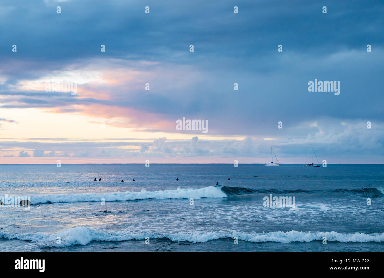 Sonnenuntergang von Hanga Roa, Rapa Nui, Chile gesehen, mit Surfern und Bodyboarder im Wasser warten auf Wellen Stockfoto