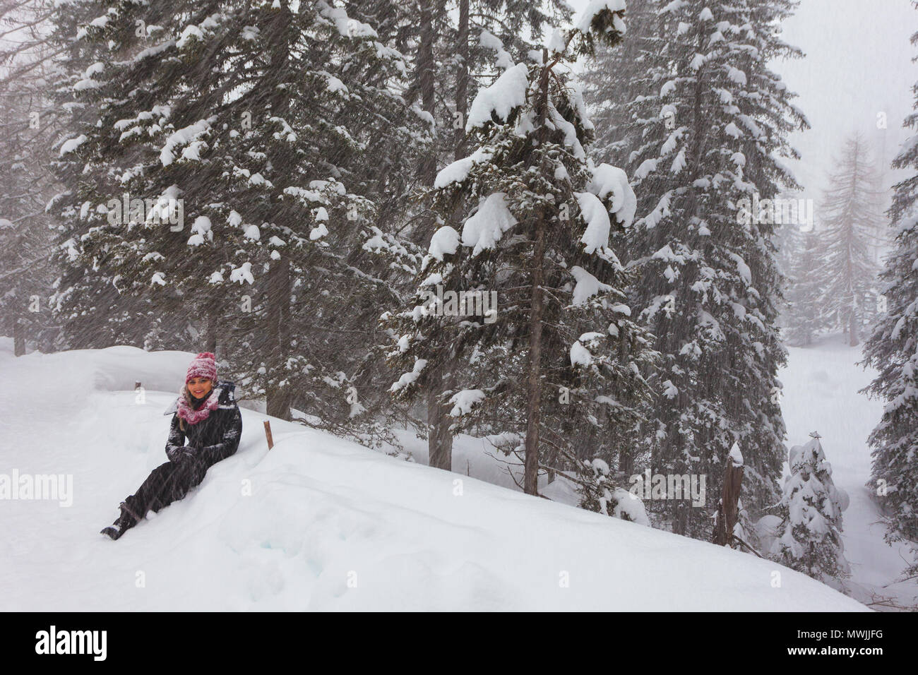 SELVA DI CADORE, ITALY - JANUARY 03 2018: Girl resting during a walk in the woods under a heavy snowfall Stockfoto