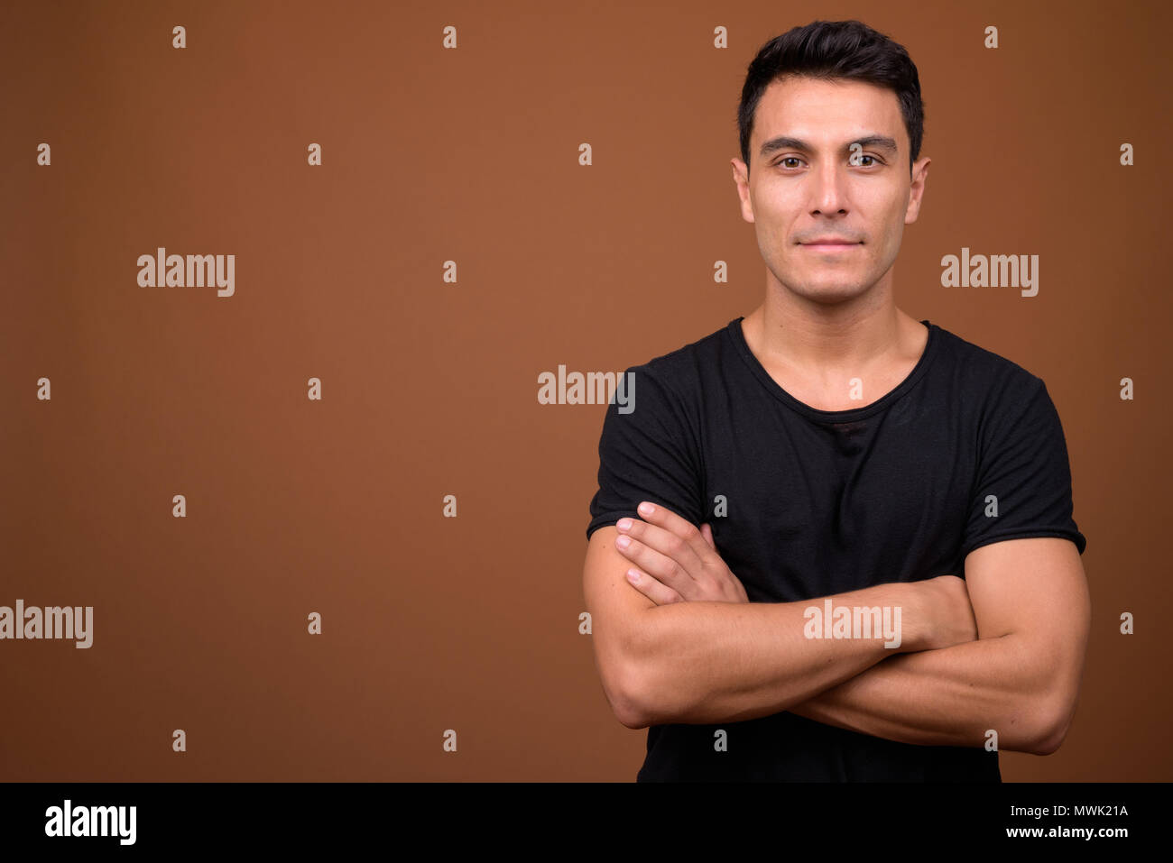 Junge schöne Hispanic Mann gegen braunen Hintergrund Stockfoto