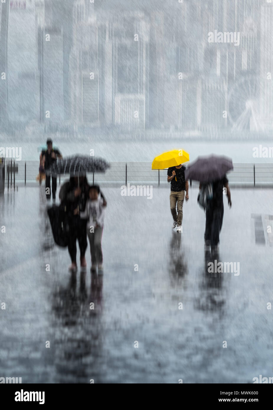 Verschwommene Menschen mit Sonnenschirmen zu Fuß durch die Straße unter dem starken Regen. Die Hong Kong Insel im Dunst auf Hintergrund. Yellow Umbrella. Stockfoto