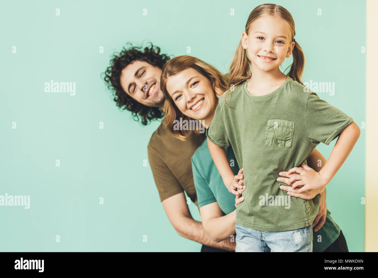 Glückliche Eltern mit süßen kleinen Tochter das Tragen von T-Shirts und lächelnd an Kamera Stockfoto