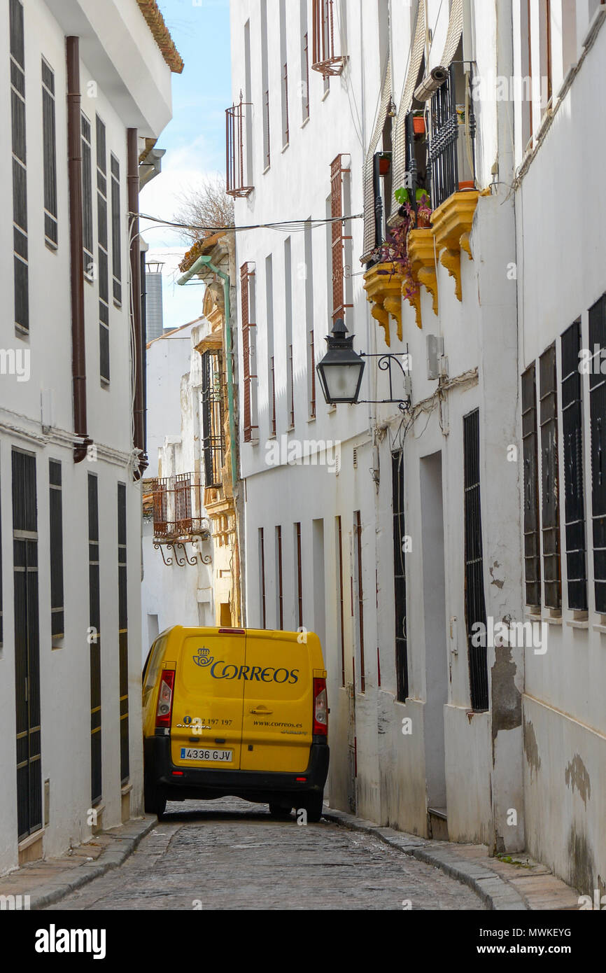 Gelb van drückt durch die engen, gepflasterten Straße in Cordoba, Spanien. Traditionelle weiß getünchte Wände, eine alte Metall streetlight, gelb Blumenkästen. Stockfoto