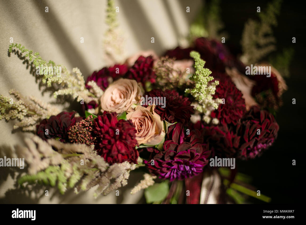 Hochzeit zerzaust Blumenstrauß mit weinroten Dahlien, creme Rosen und grünen. In der Nähe der horizontalen Foto Stockfoto