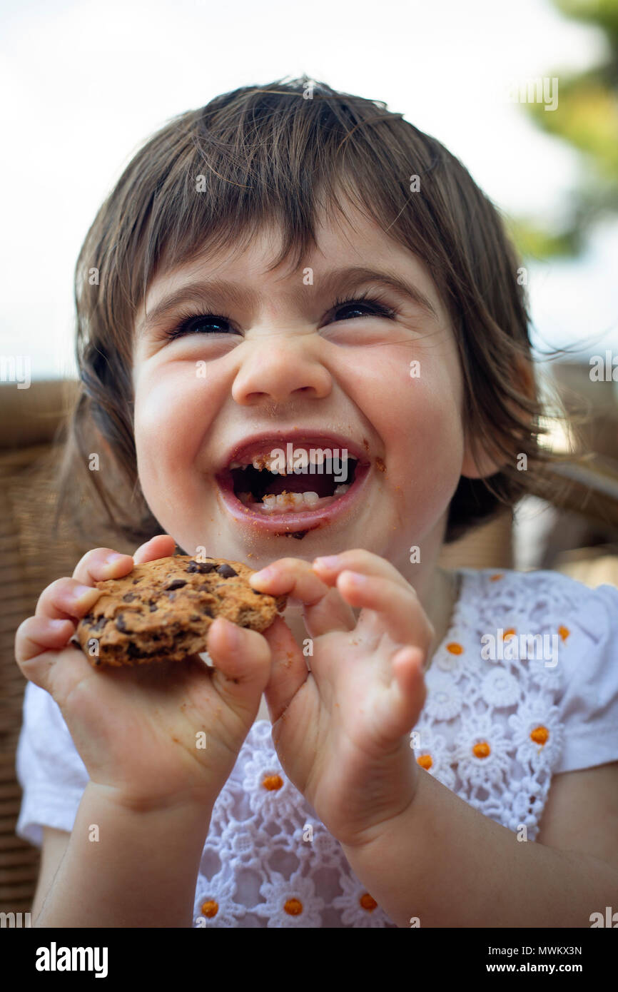 Ein 16-Monate altes Mädchen heraus lachen, wenn Sie ein Cookie isst. Stockfoto