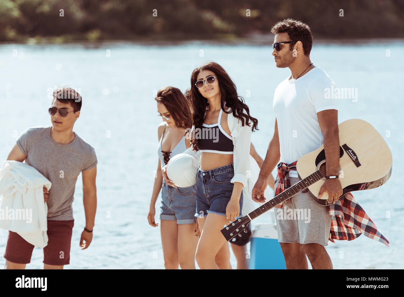 Multikulturelle junge Freunde mit Gitarre Zeit miteinander zu verbringen und Wandern am Riverside Stockfoto